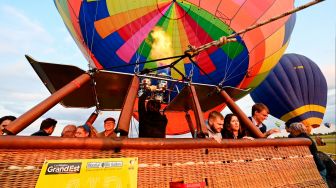 Peserta menaiki balon udara yang akan diterbangkan di pangkalan udara Chambley-Bussieres saat festival balon udara internasional ke-18 "Grand-Est Mondial Air Ballons" di Hageville, Prancis, Jumat (21/7/2023). [Jean-Christophe VERHAEGEN / AFP]