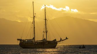 Perahu nelayan melintas di dekat kapal Arka Kinari yang membuang sauh di Pantai Mamboro, Teluk Palu, Palu, Sulawesi Tengah, Sabtu (22/7/2023). [ANTARA FOTO/Basri Marzuki/Spt]