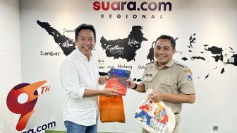 Kepala Bidang Komunikasi Publik Dinas Kominfotik DKI Jakarta, Koharudin memberikan buku tentang Jakarta ke Pemimpin Redaksi Suara.com Suwarjono usai media visit di Kantor Suara.com di kawasan Mega Kuningan, Jakarta Selatan. [Suara.com/Dwi Bowo Raharjo]