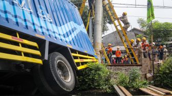 Petugas memutus aliran listrik pada tiang penyangga kabel KRL yang roboh di antara Perlintasan Pondok Ranji - Kebayoran, Jakarta, Selasa (25/7/2023). [Suara.com/Alfian Winanto]