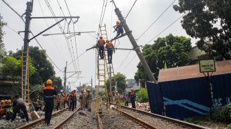 Petugas memutus aliran listrik pada tiang penyangga kabel KRL yang roboh di antara Perlintasan Pondok Ranji - Kebayoran, Jakarta, Selasa (25/7/2023). [Suara.com/Alfian Winanto]