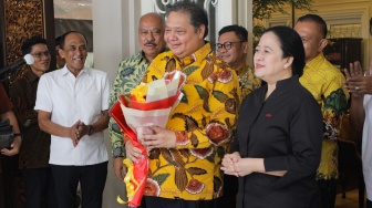 Ketua Umum Partai Golkar Airlangga Hartarto memberikan bunga kepada Ketua DPP PDIP Puan Maharani saat menggelar pertemuan di Kediaman Airlangga di Kebayoran Baru, Jakarta, Kamis (27/7/2023). [Suara.com/Alfian Winanto]