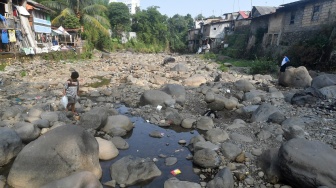 Warga berjalan di Sungai Ciliwung yang menyusut airnya di Kelurahan Babakan Pasar, Kota Bogor, Jawa Barat, Jumat (28/7/2023). [ANTARA FOTO/Arif Firmansyah].