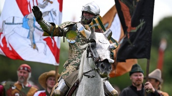 Seorang peserta selebrasi usai berhasil mengalahkan lawannya dalam acara jousting Joust Legendaris di Kastil Kenilworth, Coventry, Inggris, Sabtu (29/7/2023). [Oli SCARFF / AFP]