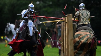 Para peserta berkompetisi di atas kuda mereka selama acara jousting Joust Legendaris di Kastil Kenilworth, Coventry, Inggris, Sabtu (29/7/2023). [Oli SCARFF / AFP]P)
