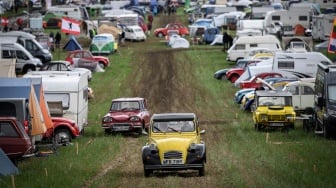 Mobil-mobil berjalan melewati kamp saat pertemuan Dunia ke-24 Citroen 2CV Friends di dekat Delemont, Swiss, Rabu (26/7/2023). [GABRIEL MONNET/AFP]