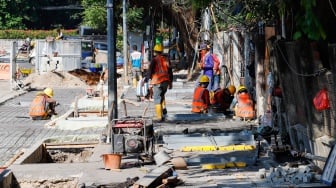 Pekerja saat menyelesaikan revitalisasi trotoar di kawasan Blok M, Jakarta Selatan, Selasa (1/8/2023).  [Suara.com/Alfian Winanto]