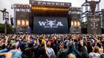 Para metalhead  bersorak saat melihat konser di depan panggung utama festival musik Wacken Open Air 2023 di Wacken, Jerman, Kamis (3/8/2023). [Axel Heimken / AFP] 