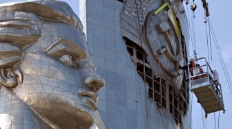 Para pekerja sedang membongkar lambang bekas Uni Soviet dari perisai Monumen Ibu Pertiwi di Kyiv, Ukraina, Selasa (1/8/2023). [Sergei SUPINSKY / AFP]
