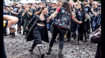 Para metalhead menari riang diatas lumpur saat festival musik Wacken Open Air 2023 di Wacken, Jerman, Kamis (3/8/2023). [Axel Heimken / AFP] 