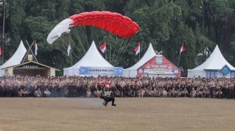 Atraksi terjun payung saat upacara pembukaan Raimuna Nasional (Rainas) XII di Bumi Perkemahan Cibubur, Jakarta, Senin (14/8/2023). [Suara.com/Alfian Winanto]