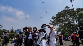 Warga berswafoto saat melihat atraksi udara di atas langit Jakarta, Kamis (17/8/2023). [Suara.com/Alfian Winanto]