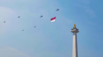 Helikopter membawa bendera merah putih melintas di Jakarta, Kamis (17/8/2023). [Suara.com/Alfian Winanto]