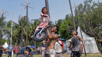 Peserta memamerkan hadiah lomba panjat pinang di Pantai Festival, Taman Impian Jaya Ancol, Jakarta, Selasa (17/8/2023). [Suara.com/Alfian Winanto]