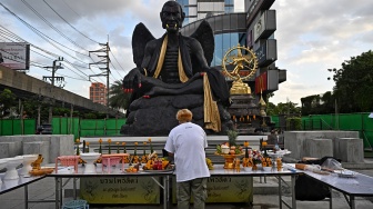 Para pemuja berkumpul di sekitar patung raksasa dewa Kru Kai Kaew di Bangkok, Thailand, Jumat (18/8/2023). [Lillian SUWANRUMPHA / AFP]

