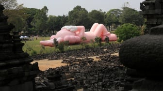 Pengunjung melihat instalasi seni dari yang dibuat oleh seniman dunia Brian Donnelly atau KAWS saat pameran bertajuk KAWS:HOLIDAY Indonesia di pelataran Candi Brahma di Kompleks Candi Prambanan, Sleman, Yogyakarta, Sabtu (19/8/2023). [DEVI RAHMAN / AFP]