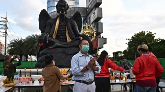 Para pemuja berkumpul di sekitar patung raksasa dewa Kru Kai Kaew di Bangkok, Thailand, Jumat (18/8/2023). [Lillian SUWANRUMPHA / AFP]

