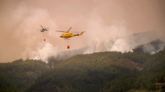 Sebuah helikopter menjatuhkan air untuk memadamkan kabakaran hutan di Tenerife, Kepulauan Canary, Spanyol, Minggu (20/8/2023). [DESIREE MARTIN / AFP]