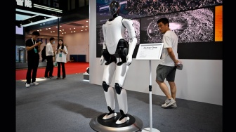 Seorang pengunjung melihat robot Xiaomi di Konferensi Robot Dunia 2023 di Beijing, China, Rabu (16/8/2023). [WANG Zhao / AFP]