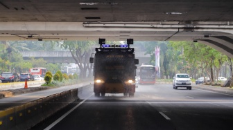 Mobil kepolisian melakukan penyiraman di kedua sisi di Jalan Jendral Sudirman hingga Patung Pemuda Membangun Senayan, Jakarta, Rabu (23/8/2023). [Suara.com/Alfian Winanto]