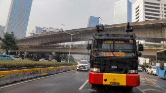 Mobil kepolisian melakukan penyiraman di kedua sisi di Jalan Jendral Sudirman hingga Patung Pemuda Membangun Senayan, Jakarta, Rabu (23/8/2023). [Suara.com/Alfian Winanto]