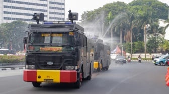 Mobil kepolisian melakukan penyiraman di kedua sisi di Jalan Jendral Sudirman hingga Patung Pemuda Membangun Senayan, Jakarta, Rabu (23/8/2023). [Suara.com/Alfian Winanto]