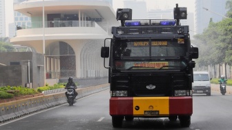 Mobil kepolisian melakukan penyiraman di kedua sisi di Jalan Jendral Sudirman hingga Patung Pemuda Membangun Senayan, Jakarta, Rabu (23/8/2023). [Suara.com/Alfian Winanto]