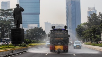 Mobil kepolisian melakukan penyiraman di kedua sisi di Jalan Jendral Sudirman hingga Patung Pemuda Membangun Senayan, Jakarta, Rabu (23/8/2023). [Suara.com/Alfian Winanto]