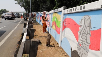 Petugas Penanganan Prasarana dan Sarana Umum (PPSU) membuat mural di Jalan Haji Bokir bin Djiun, Kramat Jati, Jakarta Timur, Kamis (24/8/2023). [Suara.com/Alfian Winanto]