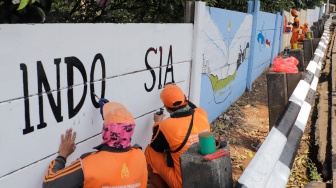 Petugas Penanganan Prasarana dan Sarana Umum (PPSU) membuat mural di Jalan Haji Bokir bin Djiun, Kramat Jati, Jakarta Timur, Kamis (24/8/2023). [Suara.com/Alfian Winanto]