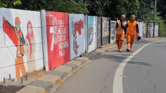 Petugas Penanganan Prasarana dan Sarana Umum (PPSU) membuat mural di Jalan Haji Bokir bin Djiun, Kramat Jati, Jakarta Timur, Kamis (24/8/2023). [Suara.com/Alfian Winanto]