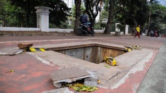 Warga berjalan menghindari lubang saluran kabel di Jalan Raya Casablanca, Jakarta, Jumat (25/8/2023). [Suara.com/Alfian Winanto]