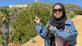 Putri Ariani menunjuk bukit Hollywood yang menjadi landmark kota Los Angeles. [Instagram]