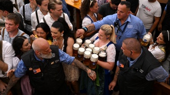 Seorang pramusaji membawa cangkir bir di tenda festival saat pembukaan Oktoberfest 2023 di Munich, Jerman, Sabtu (16/9/2023). [Christof STACHE / AFP]
