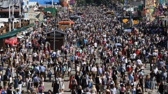 Pengunjung berjalan di tempat pameran Theresienwiese pada hari pembukaan Oktoberfest 2023 di Munich, Jerman, Sabtu (16/9/2023). [Christof STACHE / AFP]
