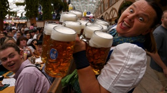 Reaksi seorang pramusaji ketika membawa cangkir bir di tenda festival saat pembukaan Oktoberfest 2023 di Munich, Jerman, Sabtu (16/9/2023). [Christof STACHE / AFP]