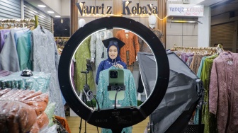 Pedagang menjual pakaian secara daring melalui sosial media Tik-tok Live di Blok A Pasar Tanah Abang, Jakarta, Selasa (19/9/2023). [Suara.com/Alfian Winanto]

