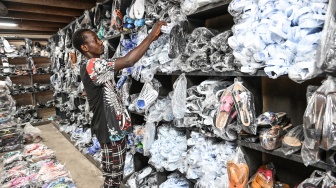 Seorang karyawan mengatur sandal leke di sebuah toko di Treichville, Abidjan, Pantai Gading, Kamis (14/9/2023). [Sia KAMBOU / AFP]
