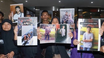 Keluarga Korban Tragedi Kanjuruhan menunjukkan poster berisi foto keluarga mereka yang menjadi korban saat mendatangi Bareskrim Mabes Polri, Jakarta, Rabu (27/9/2023). [Suara.com/Alfian Winanto]