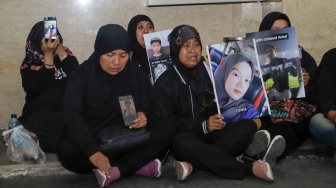 Keluarga Korban Tragedi Kanjuruhan menunjukkan poster berisi foto keluarga mereka yang menjadi korban saat mendatangi Bareskrim Mabes Polri, Jakarta, Rabu (27/9/2023). [Suara.com/Alfian Winanto]