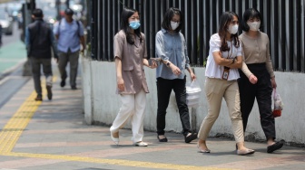 Pekerja melintasi pelican crossing di Jakarta, Senin (9/10/2023). [Suara.com/Alfian Winanto]