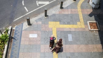 Pekerja melintasi pelican crossing di Jakarta, Senin (9/10/2023). [Suara.com/Alfian Winanto]