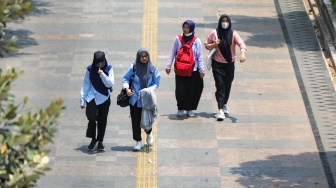 Pekerja melintasi pelican crossing di Jakarta, Senin (9/10/2023). [Suara.com/Alfian Winanto]