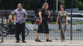 Pekerja melintasi pelican crossing di Jakarta, Senin (9/10/2023). [Suara.com/Alfian Winanto]