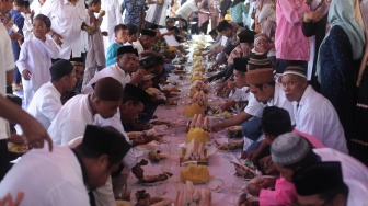 Sejumlah warga makan bersama usai ritual tolak bala Uci Dowong atau turun ke pesisir pantai untuk memanjatkan doa kepada leluhur terdahulu di Pantai Wisata Sulamadaha, Kota Ternate, Maluku Utara, Senin (16/10/2023). [ANTARA FOTO/Andri Saputra/tom]