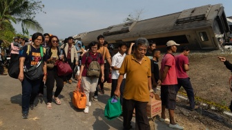 Penumpang membawa barang bawaan mereka di dekat gerbong kereta api yang anjlok akibat kecelakaan di kawasan Kalimenur, Sukoreno, Kulonprogo, D.I Yogyakarta, Selasa (17/10/2023). [ANTARA FOTO/Andreas Fitri Atmoko].