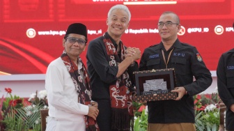 Bakal calon Presiden Ganjar Pranowo (tengah) bersama bakal calon Wakil Presiden Mahfud MD (kiri) dan Ketua KPU Hasyim Asy'ari (kanan) saat melakukan pendaftaran Calon Presiden dan Wakil Presiden Pemilihan Umum 2024 di Gedung KPU, Jakarta, Kamis (19/10/2023). [Suara.com/Alfian Winanto]
