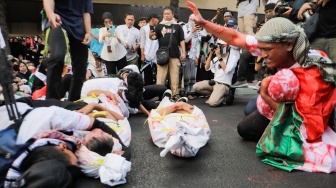 Massa aksi melakukan aksi teaterikal saat unjuk rasa di depan kantor perwakilan Perserikatan Bangsa-Bangsa (PBB) di Jakarta, Jumat (20/10/2023). [Suara.com/Alfian Winanto]