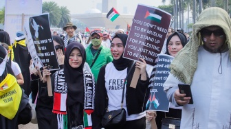 Massa aksi membawa poster dukungan untuk Palestina saat Aksi Damai Bela Palestina di Monas, Jakarta, Minggu (5/11/2023). [Suara.com/Alfian Winanto]