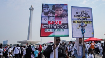 Massa aksi membawa poster dukungan untuk Palestina saat Aksi Damai Bela Palestina di Monas, Jakarta, Minggu (5/11/2023). [Suara.com/Alfian Winanto]